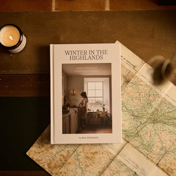 Book titled 'Winter in the Highlands' on a wooden surface with a map and candle.